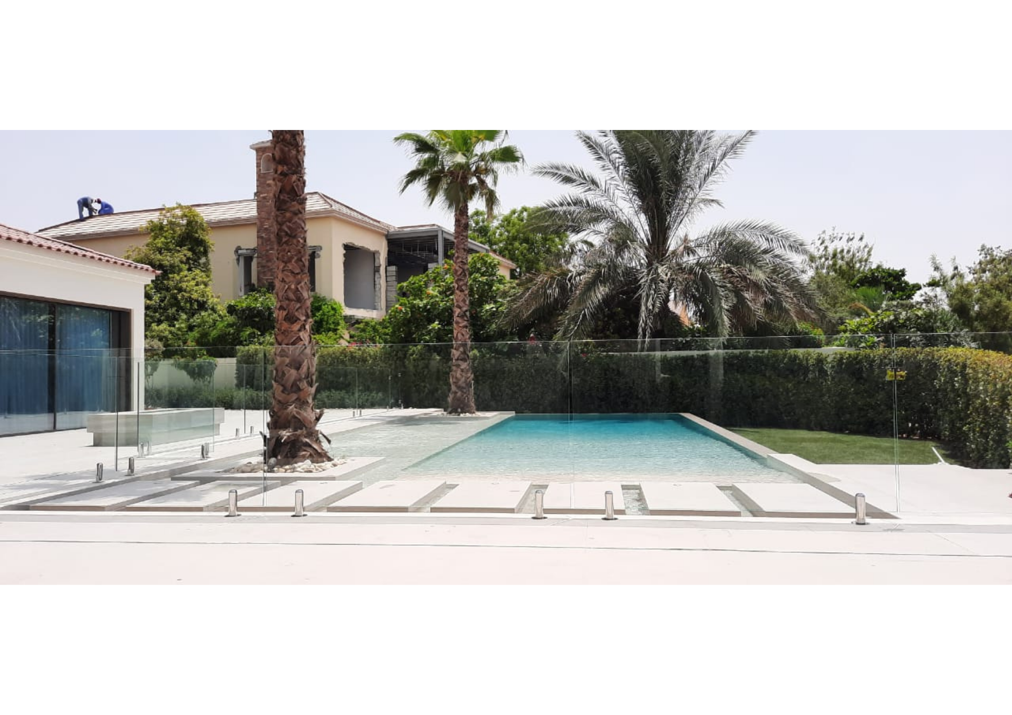 Frameless glass pool fence at a luxury Dubai villa with palm trees