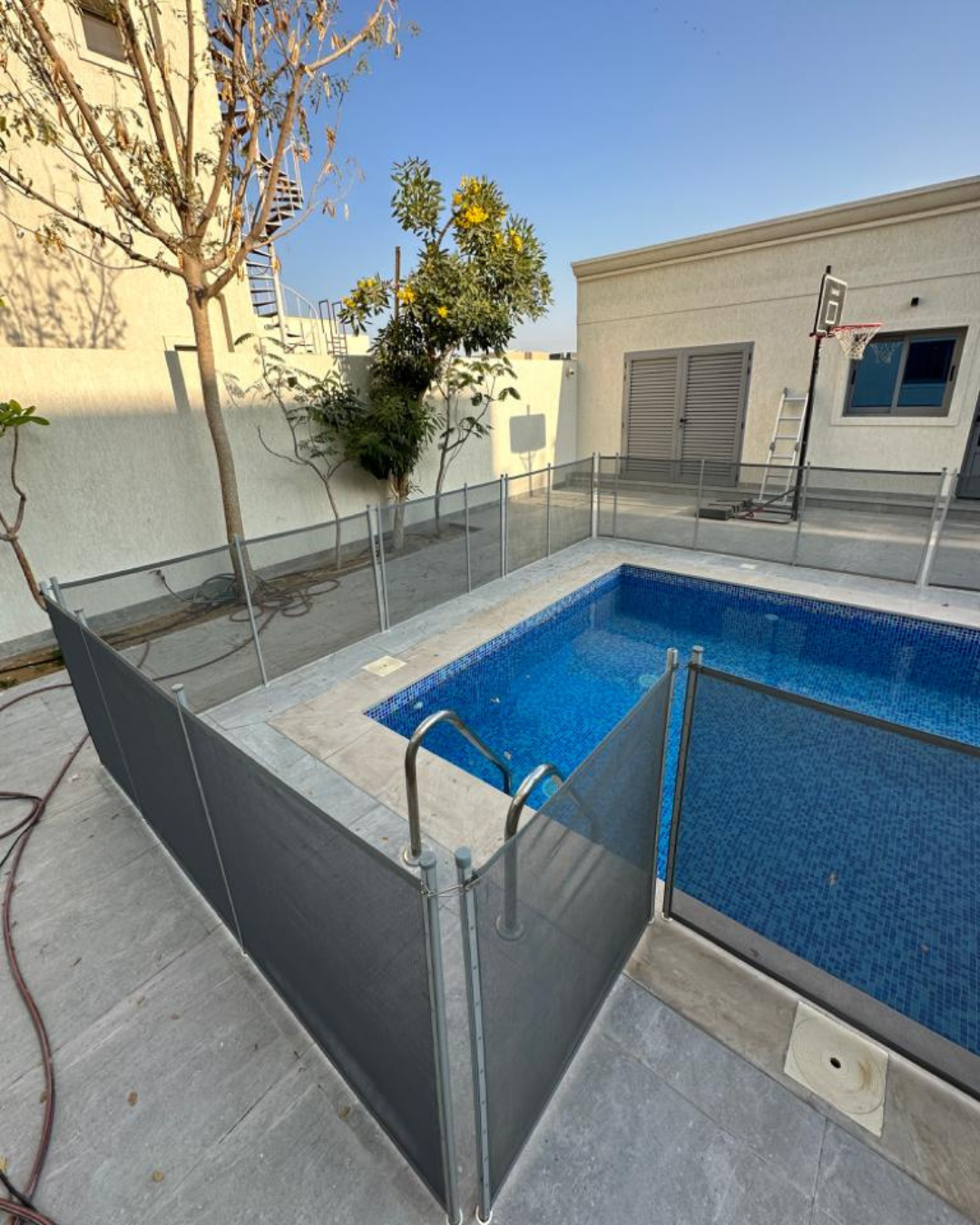 Black mesh pool safety fence around a villa pool with stone deck